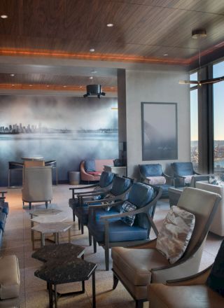 A modern lounge area with comfortable seating, large windows with a scenic water view, and a wall mural featuring a city skyline ends the sentence.