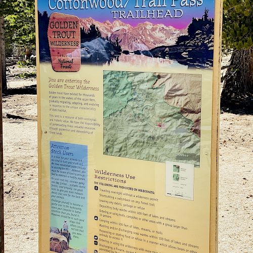 The image shows an informational sign for Cottonwood/Trail Pass Trailhead featuring a map, trail details, a permit notice, and guidance to preserve the wild.