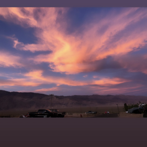 A stunning sunset with vibrant orange and purple clouds over a mountainous landscape, creating a breathtaking and tranquil scene.